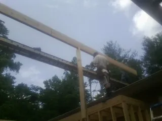 Carpenter setting a ridge beam over a new addition frame — Ice Dam Removal by Roofing Brothers in Woods Hole