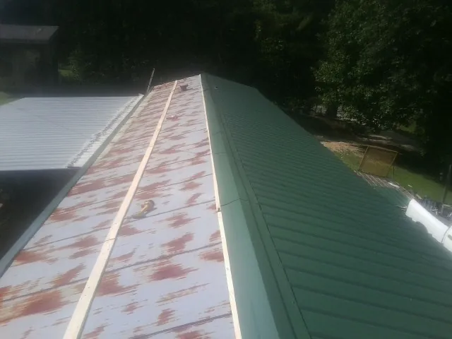 Old rusted panels beside newly installed green metal roofing — Wind Damage Roof Repair by Roofing Brothers in Woods Hole