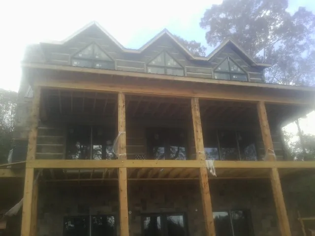 Dormers and porch framing on a large log home under construction — Roof Coating work by our crew in Woods Hole