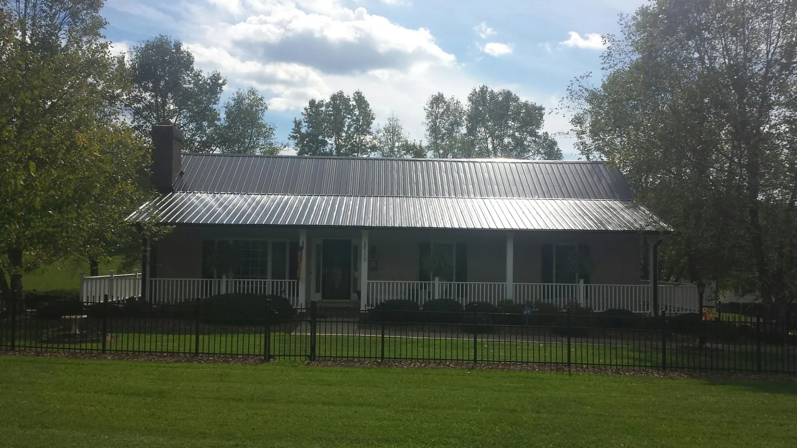 Gray metal roof on a brick ranch with a full width front porch — Gutter Guard Installation work by our crew in Woods Hole