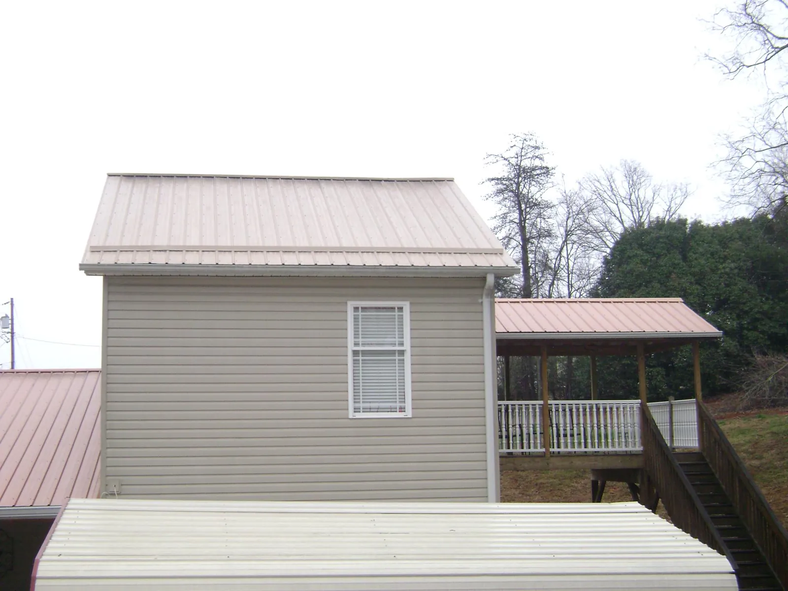 Tan metal roofs on a two story addition and attached porch, from a Roof Replacement job in Woods Hole